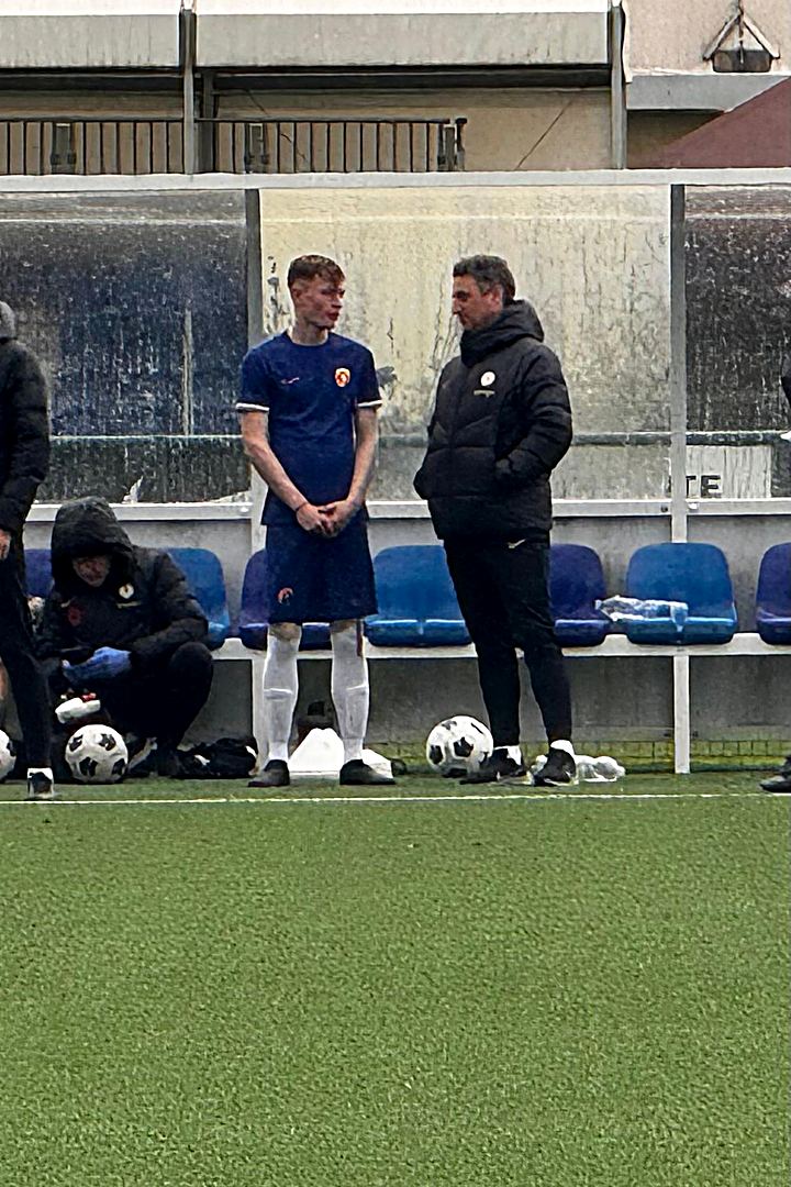 Jack talking with a coach pitchside at a Chelsea trial.